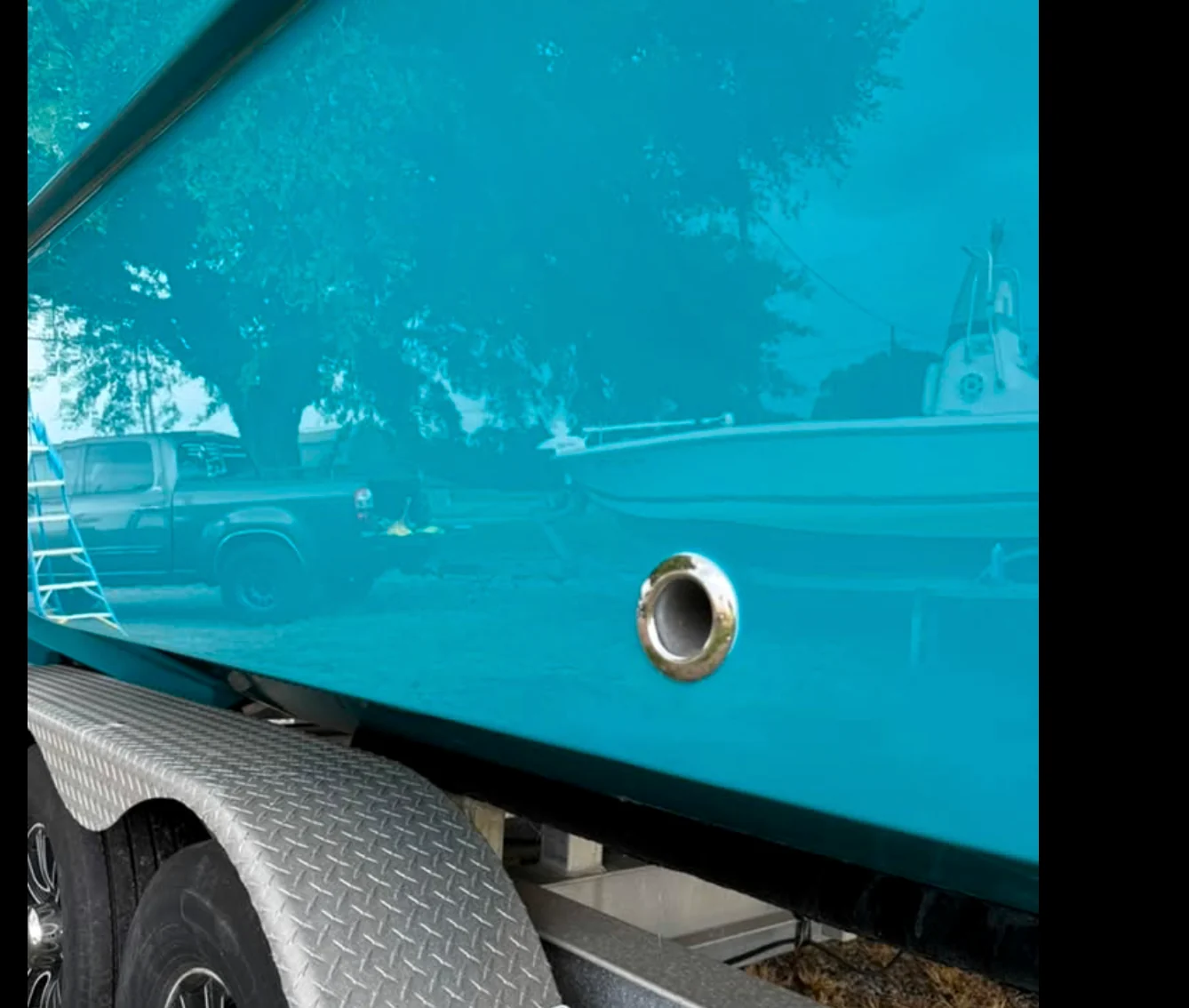 Glossy turquoise boat hull reflecting the surroundings